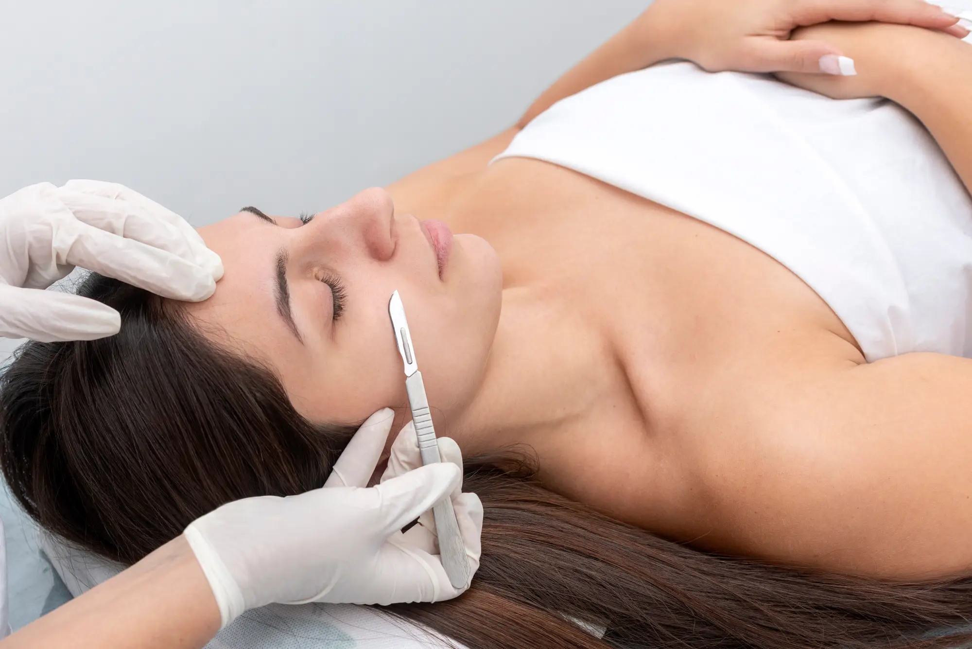 a woman lying down with tweezers on her face with Dermaplaning in Cary, NC