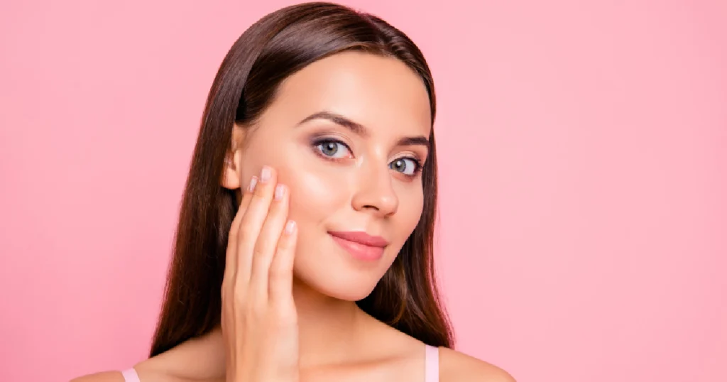 Woman with smooth glowing skin touching her face after Dermaplaning in Cary, NC.